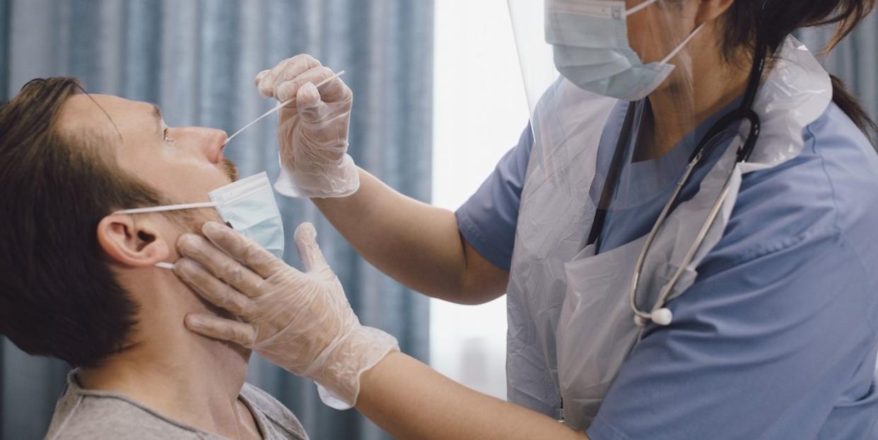 female doctor taking swab test of male patient in clinic during covid 19