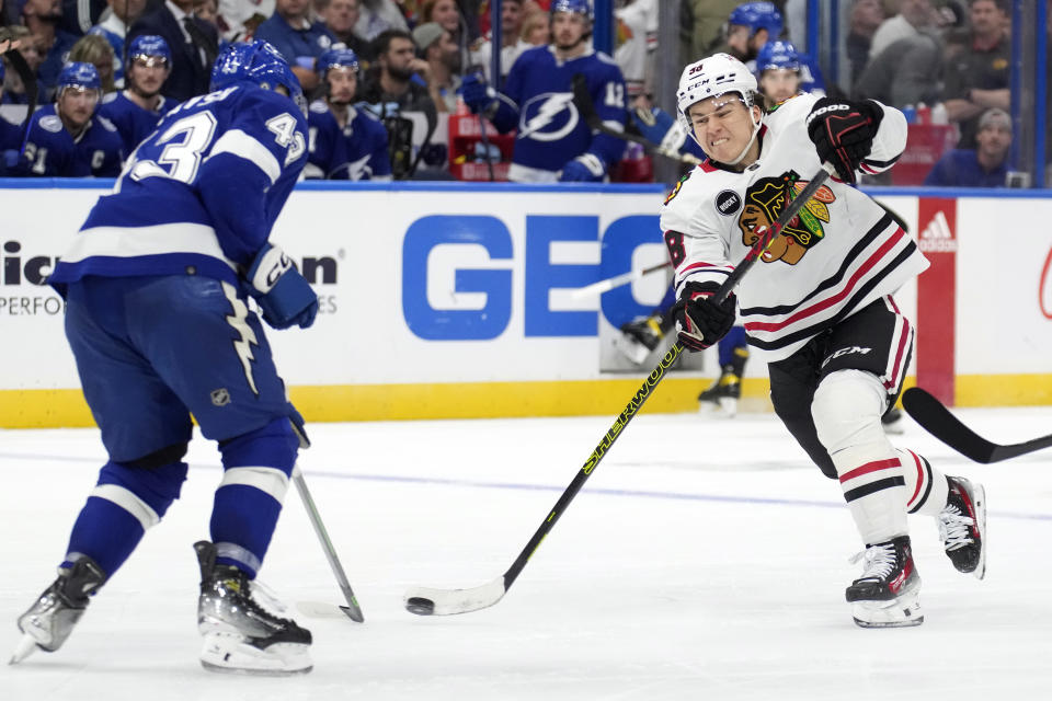 Chicago Blackhawks center Connor Bedard (98) shoots in front of Tampa Bay Lightning defenseman Darren Raddysh (43) during the third period of an NHL hockey game Thursday, Nov. 9, 2023, in Tampa, Fla. (AP Photo/Chris O'Meara)
