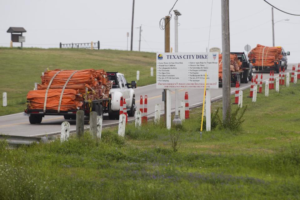 Environmental personnel drive onto the Texas City Dike with oil containment booms for oil remediation following a barge collision in the ship channel, causing an oil spill Saturday, March 22, 2014, in Houston. The barge carried 924,000 gallons of fuel oil. (AP Photo/ Houston Chronicle, Brett Coomer)