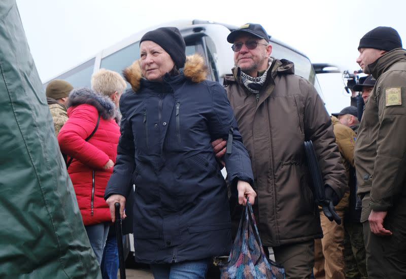 People walk past Ukrainian servicemen and officials following prisoner of war exchange in Donetsk region