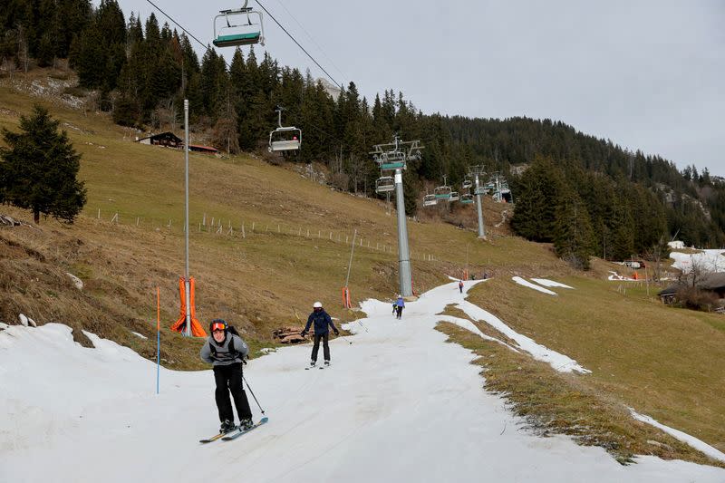 Skiers pass on a small layer of artificial snow in Leysin