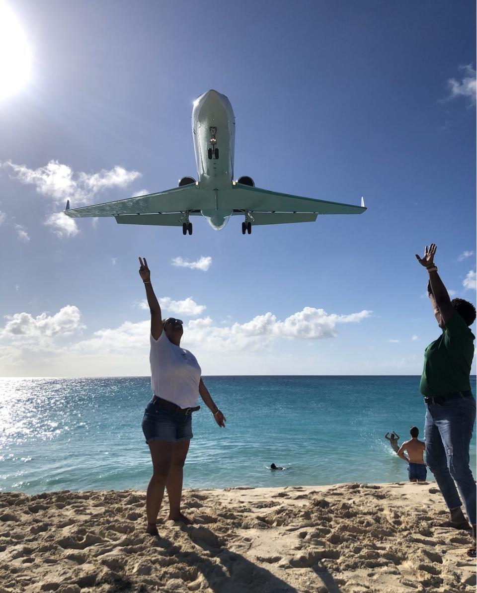 Onlookers reach up toward airplanes flying low over Maho Beach in St. Martin.