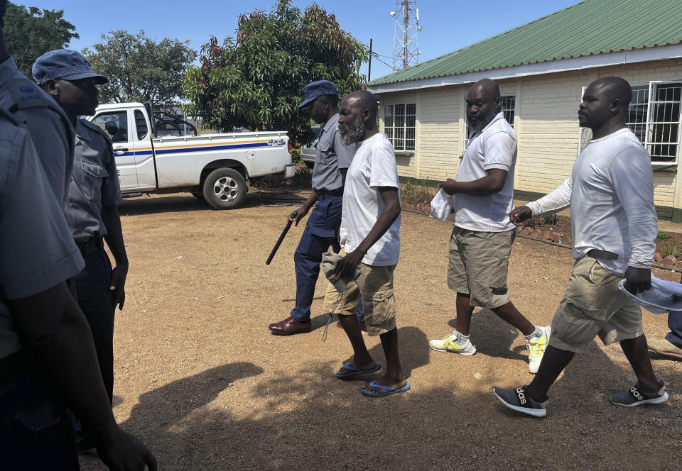 Ishmael Chokurongerwa , 56, in blue flip flops a "self styled" prophet arrives for his court appearance accompanied by his aides in Norton about 40 kilometres west of the capital, Harare, Thursday, March, 14, 2024. Chokurongerwa led a sect with more than 100 members. Zimbabwean police on Wednesday said they arresteded a man claiming to be a prophet of an apostolic sect at a shrine where believers stay in a compound and authorities found 16 unregistered graves, including those of infants, and more than 250 children used as cheap labor. (AP Photo)