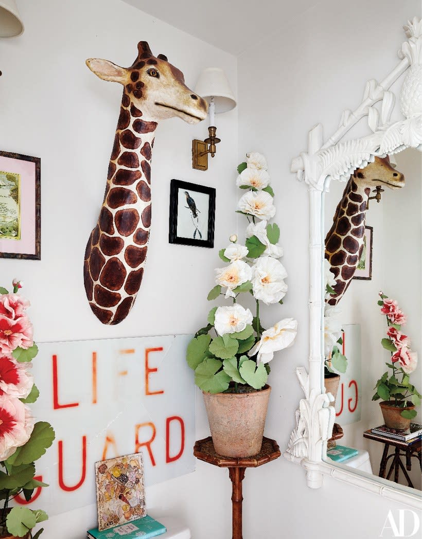 A papier-mâché giraffe bust and paper "plant" from John Derian Company holds court beside a Palm Beach Regency mirror.