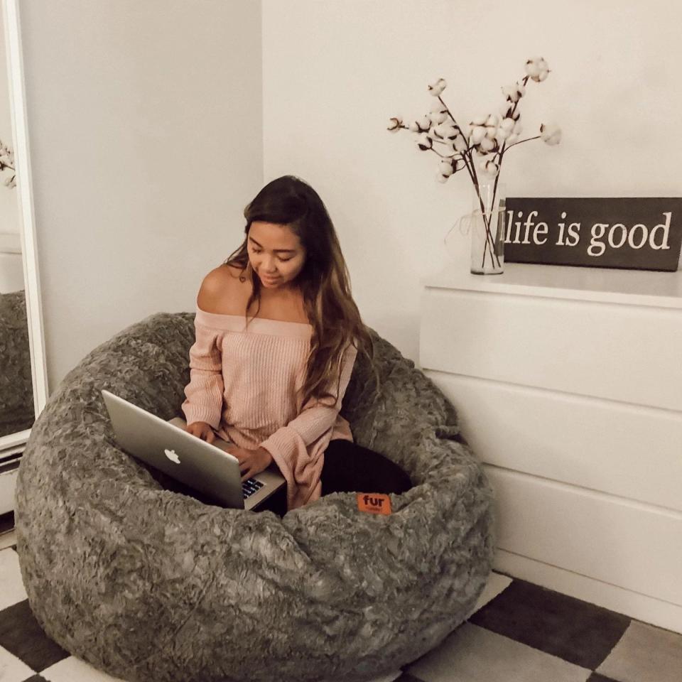 Woman looking at her laptop in a bedroom on a Cordaroys beanbag.