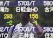 A man wipes his head as he is reflected on a stock quotation board outside a brokerage in Tokyo June 10, 2014. REUTERS/Issei Kato