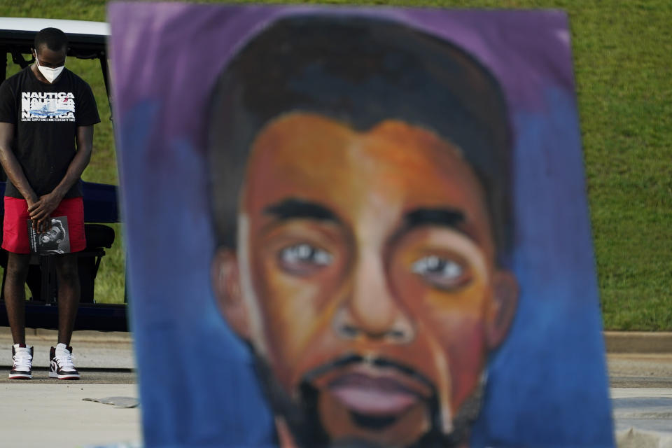 A man prays behind a painting of Chadwick Boseman during a tribute to Boseman's life on Thursday, Sept. 3, 2020, in Anderson, S.C. (AP Photo/Brynn Anderson)