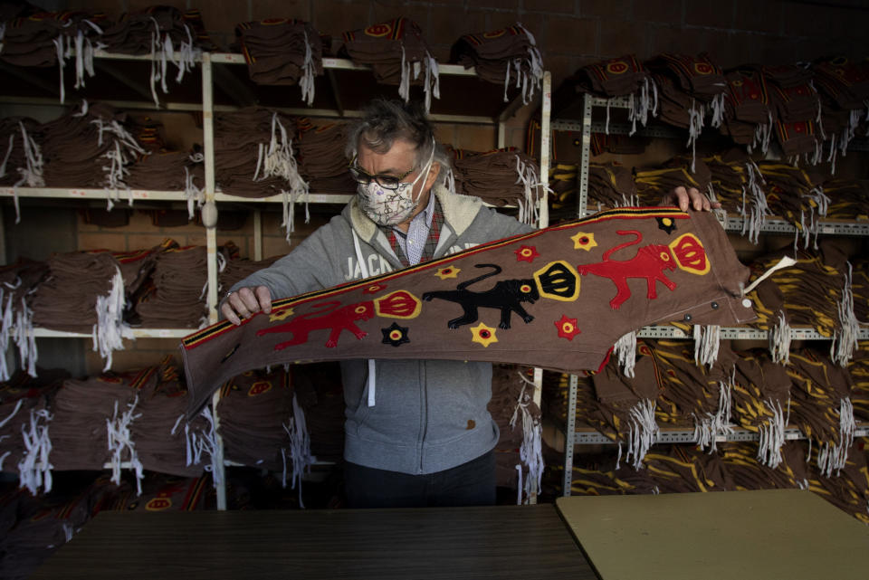 Tailor Karl Kersten folds a pair of trousers which are part of the Gilles de Binche costume at his atelier in Binche, Belgium, Thursday, Feb. 11, 2021. The economic impact of the cancellation of this years carnival due to COVID-19 will be difficult for local craftspersons who rely on the income. Kersten, a fourth-generation tailor of Gilles de Binche costumes, spends all year preparing for the event and rents about 1,000 costumes. In normal life, the small town of Binche would be bursting with excitement as craftsmen put the finishing touches to vibrant costumes, but in 2021 the COVID-19 regulations have forced the carnival to be cancelled.(AP Photo/Virginia Mayo)