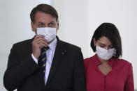 Wearing masks to curb the spread of the new coronavirus, Brazil's President Jair Bolsonaro and his wife Michelle Bolsonaro, arrive to attend the launching of a rights guarantee program for rural women, at the Planalto Presidential Palace in Brasilia, Brazil, Wednesday, July 29, 2020. (AP Photo/Eraldo Peres)