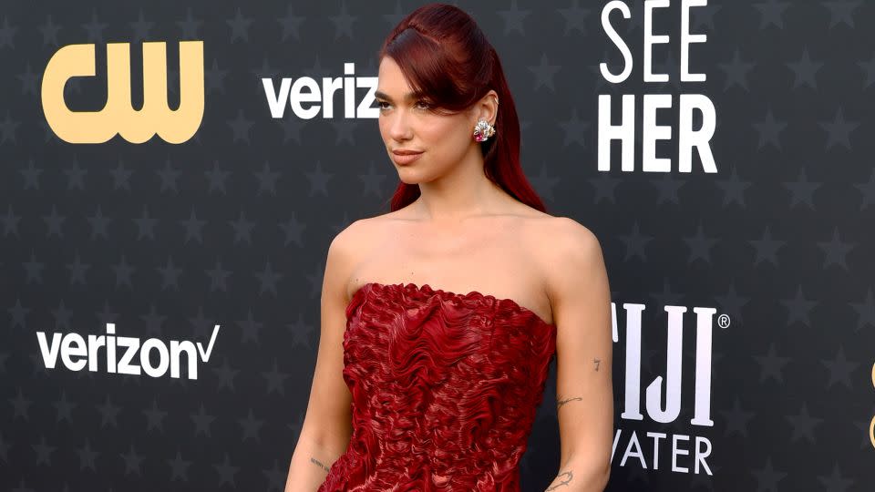 Dua Lipa, whose track "Dance the Night" (from "Barbie") was nominated for Best Song, wore a custom red Prada column dress with cascading curls, which matched her hair, and Tiffany & Co. jewelry. - Frazer Harrison/Getty Images