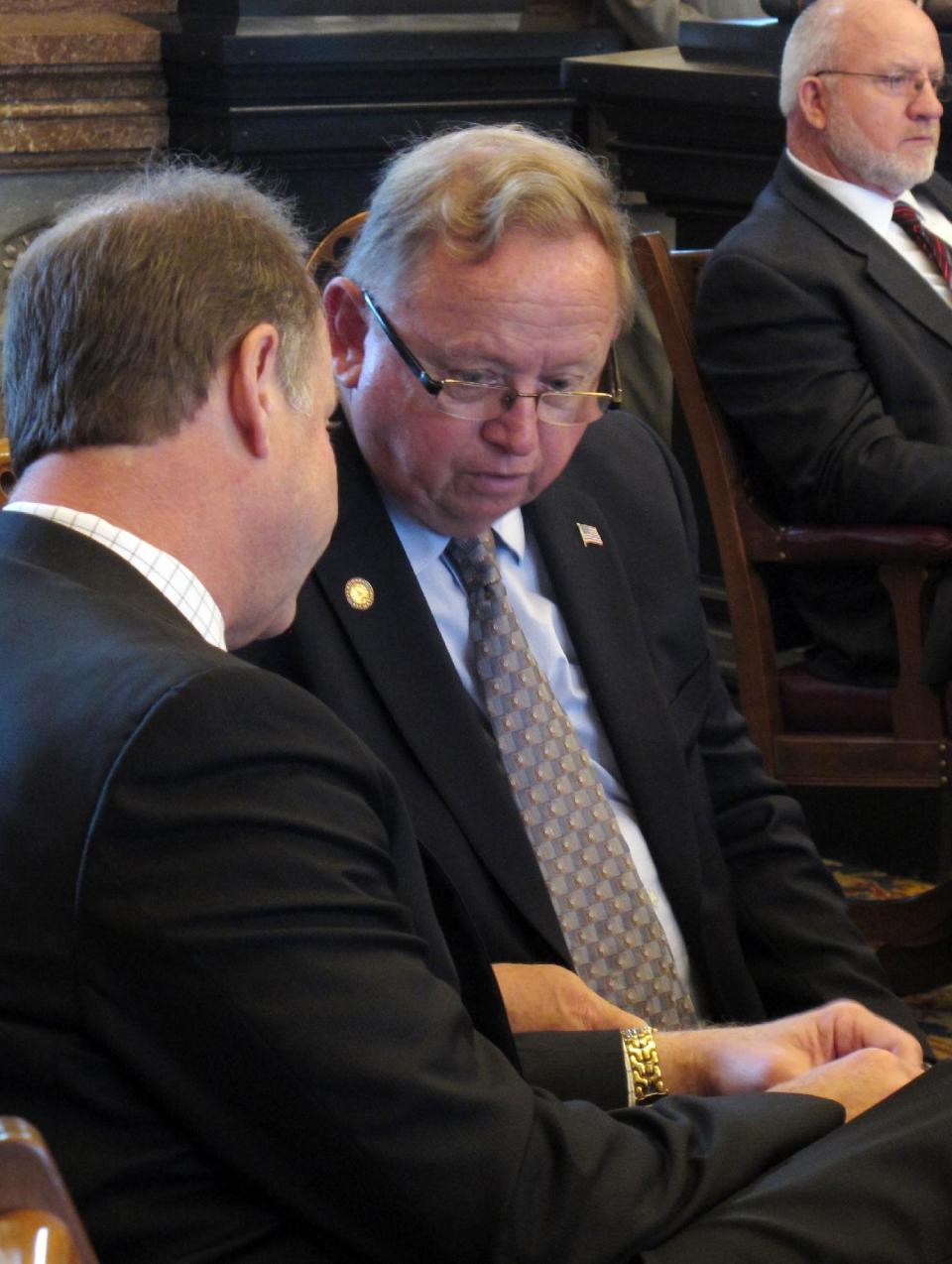 Kansas state Sens. Jeff Longbine, left, of Emporia, and Dick Kelsey, right, of center, of Goddard, confer during the Senate's session, Wednesday, March 21, 2012, at the Statehouse in Topeka, Kan. To their right is Sen. Dwayne Umbarger, a Thayer Republican, and all three switched their votes on a bill cutting sales and income taxes to help it pass. (AP Photo/John Hanna)