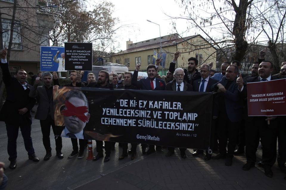 Protesters carry a banner with a crossed-out picture of Swedish politician Rasmus Paludan and a Quranic verse reading "Say this: Oh non-believers, you will be defeated and you shall be gathered and exiled unto hell" during a demonstration outside the Swedish embassy in Ankara, Turkey, Saturday, Jan. 21, 2023. Far-right activist Paludan has received permission from police to stage a protest outside the Turkish Embassy in Stockholm, where he intends to burn the Quran, Islam's holy book. (AP Photo/Burhan Ozbilici)