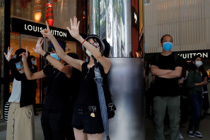 Anti-government demonstrators raise their hands up as a symbol of the "Five demands, not one less" during a protest at Central District against the second reading of a controversial national anthem law in Hong Kong