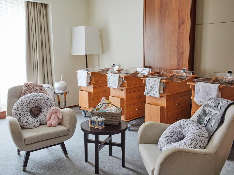 A view of the nursery, known as the baby room, at Boram Postnatal Retreat that shows four bassinets in line near the wall and two armchairs with nursing cushions on the seats.