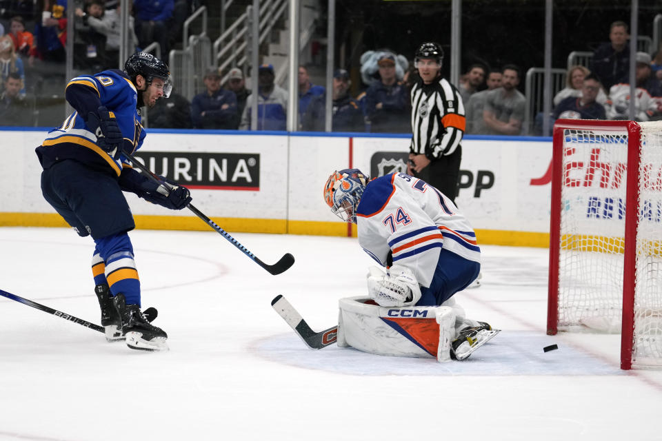 St. Louis Blues' Brandon Saad, left, scores the game-winning goal past Edmonton Oilers goaltender Stuart Skinner (74) during overtime of an NHL hockey game Monday, April 1, 2024, in St. Louis. (AP Photo/Jeff Roberson)