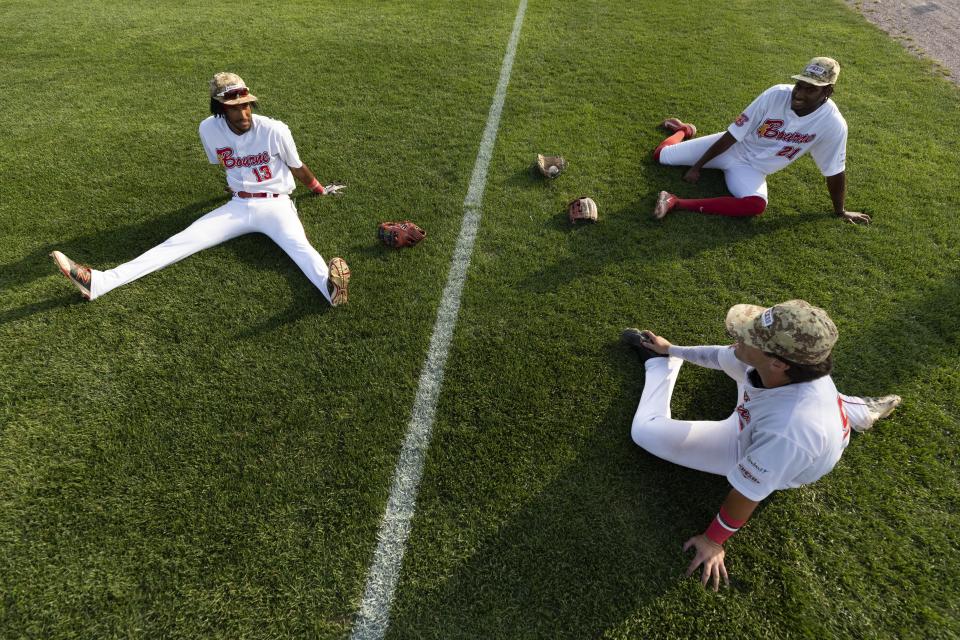 Bourne Braves players warm up before a Cape Cod League baseball game against the Chatham Anglers, Wednesday, July 12, 2023, in Bourne, Mass. For 100 years, the Cape Cod League has given top college players the opportunity to hone their skills and show off for scouts while facing other top talent from around the country. (AP Photo/Michael Dwyer)