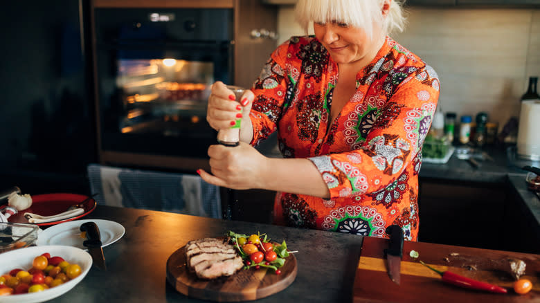 Woman seasoning sliced meat on board