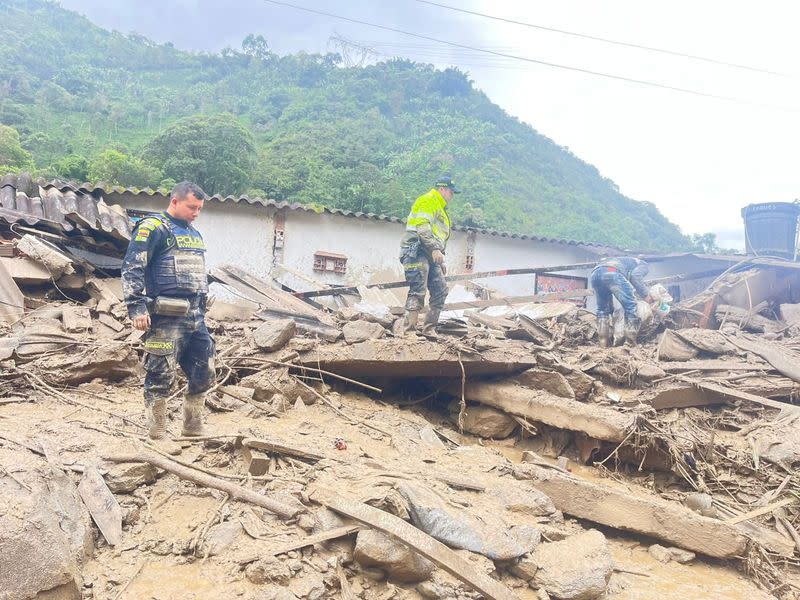 Efectivos de la Policía Nacional de Colombia inspeccionan una zona afectada por un deslizamiento de tierra, que dejó varias víctimas, en Quetame