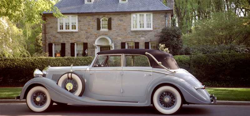 A nice car sits in front of a nice house.