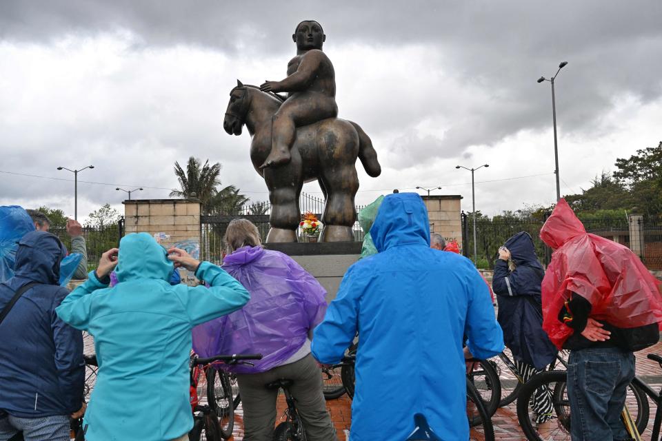 Tourists on bicycles look at a statue by the late Colombian artist Fernando Botero in Bogota, on Sept. 15, 2023.