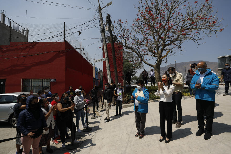 Mexico City Mayor Claudia Sheinbaum greets neighborhood residents who gathered to watch from a distance during the inauguration of a new aerial public transit system dubbed the Cablebus, at the Campos Revolucion station in the Cuautepec neighborhood of northern Mexico City, Thursday, March 4, 2021. For the residents of Cuautepec, this new system, the first of four planned lines, will turn a commute to the nearest subway station, that can last up to two hours, into a 30-minute ride. (AP Photo/Rebecca Blackwell)