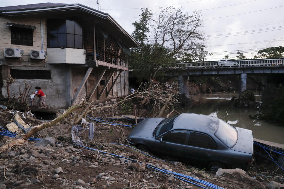 A woman walks past a car that was swept by floodwaters caused by Typhoon Goni in Batangas city, Batangas province, south of Manila, Philippines on Monday, Nov. 2, 2020. Super typhoon Goni left wide destruction as it slammed into the eastern Philippines with ferocious winds early Sunday and about a million people have been evacuated in its projected path. (AP Photo/Aaron Favila)