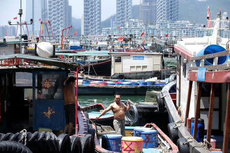 A fisherman works on an anchored boat at a fishing harbour, as Typhoon Mangkhut approaches, in Shenzhen, China September 15, 2018. REUTERS/Jason Lee