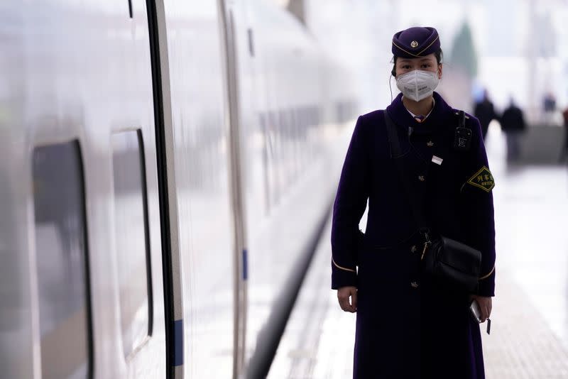 A train staff wearing a mask is seen at the Shanghai railway station in Shanghai