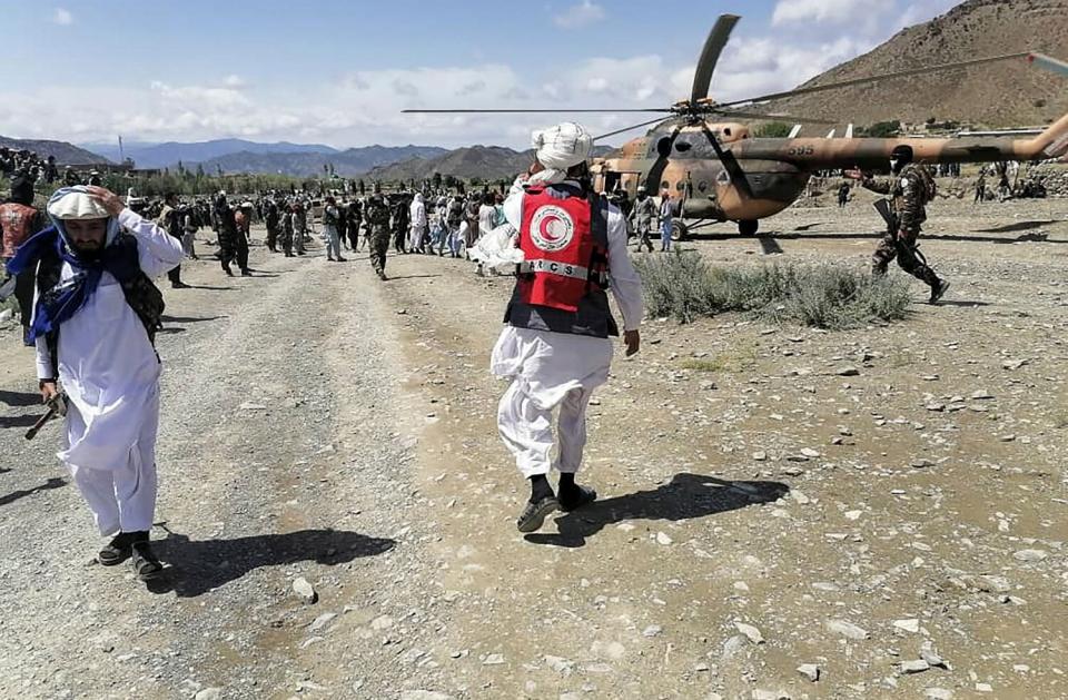 This photograph taken on June 22, 2022 and received as a courtesy of the Afghan government-run Bakhtar News Agency shows soldiers and Afghan Red Crescent Society officials near a helicopter at an earthquake hit area in Afghanistan's Gayan district