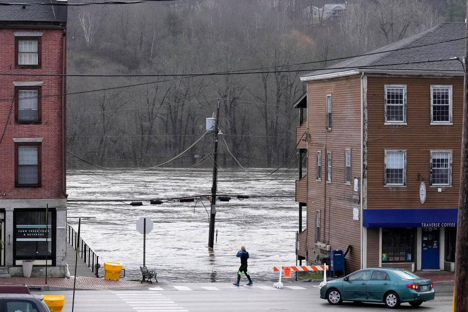 A man photographs the flooded Kennebec River, Tuesday, Dec. 19, 2023, in Hallowell, Maine. Waters continue to rise following Monday's severe storm. (AP Photo/Robert F. Bukaty)