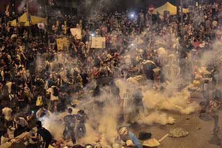 Protesters flee from teargas fired by riot police, during clashes after thousands of protesters blocked the main street to the financial Central district outside the government headquarters in Hong Kong September 28, 2014. REUTERS/Stringer