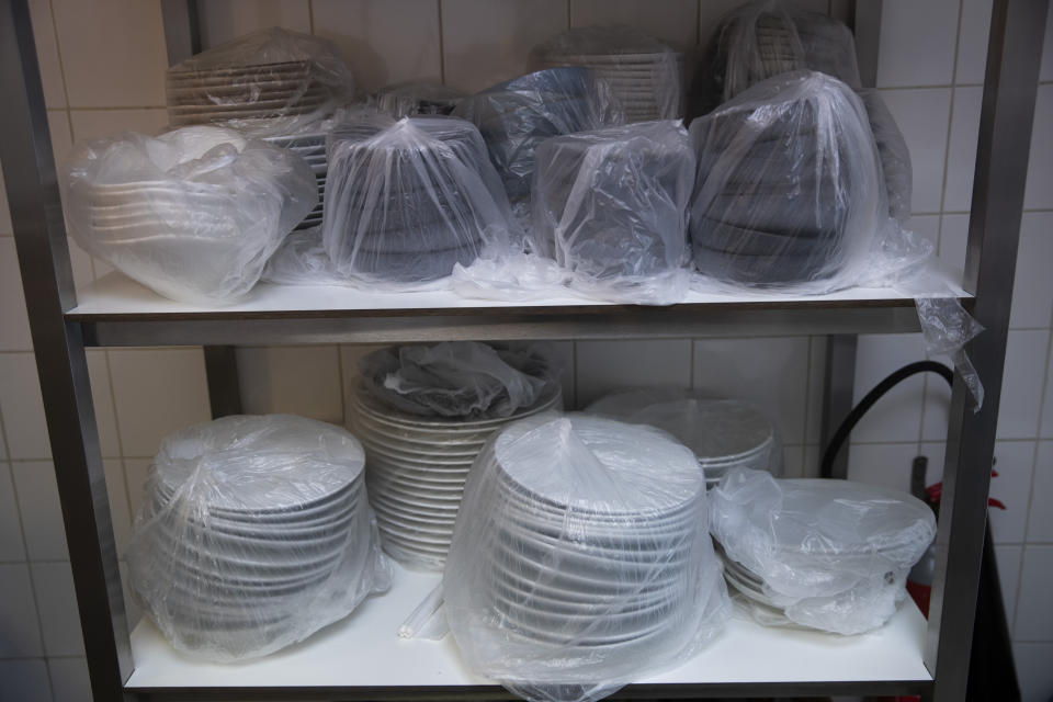 Dinner service plates are covered in plastic and stored away at the restaurant, Tartufo, in Sint-Pieters-Leeuw, Belgium, Thursday, Oct. 22, 2020. Tartufo, a successful dinner restaurant has now been forced to be inventive with take-away service. The coronavirus pandemic is gathering strength again in Europe and, with winter coming, its restaurant industry is struggling. The spring lockdowns were already devastating for many, and now a new set restrictions is dealing a second blow. Some governments have ordered restaurants closed; others have imposed restrictions curtailing how they operate. (AP Photo/Francisco Seco)