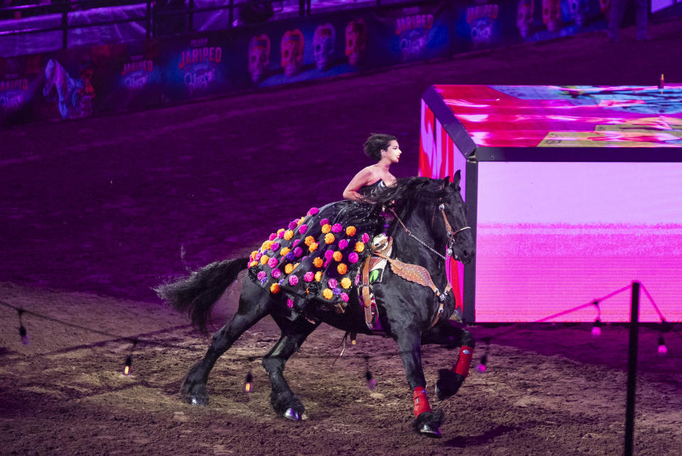 Ángela Aguilar, hija de Pepe Aguilar, monta un caballo al cantar en el espectáculo "Jaripeo hasta los huesos tour 2024" en el Honda Center en Anaheim, California, el viernes 29 de marzo de 2024. El espectáculo rinde homenaje al Día de Muertos, una conocida celebración mexicana. (Foto AP/Damian Dovarganes)