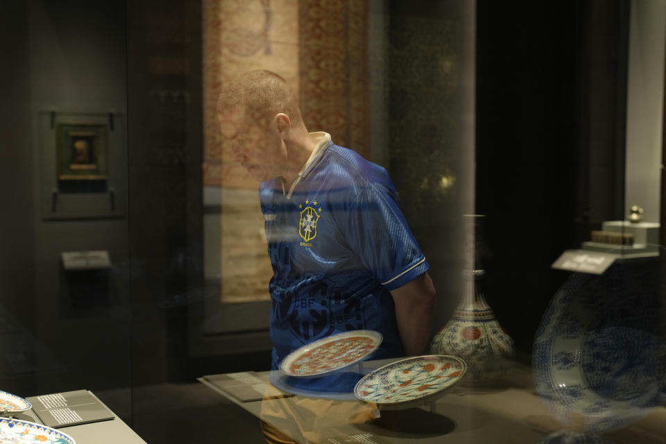 A man wearing a Brazil soccer shirt walks past a bowl from Iran at the Museum of Islamic Art in Doha, Qatar, Tuesday, Nov. 22, 2022. (AP Photo/Christophe Ena)