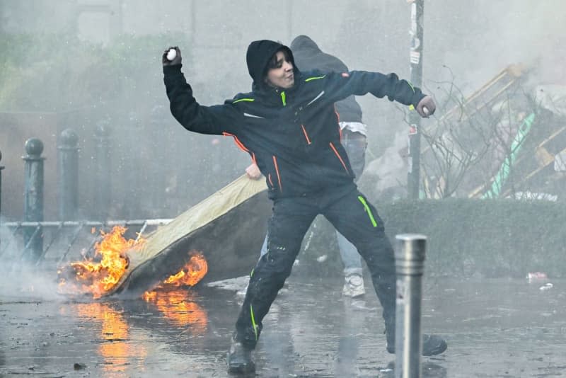 A demonstrator throws an egg during a protest by farmers in the European Quarter as European leaders gather for an EU summit in Brussels. Dirk Waem/Belga/dpa