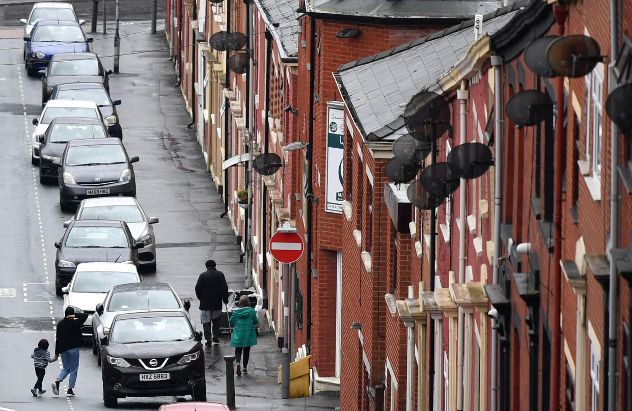 Pedestrians walk past rows of terraced houses in a residential street in Blackburn, north west England, on July 15, 2020, following news that there has been a spike in the number novel coronavirus COVID-19 cases in the area. (Photo by Paul ELLIS / AFP) (Photo by PAUL ELLIS/AFP via Getty Images)