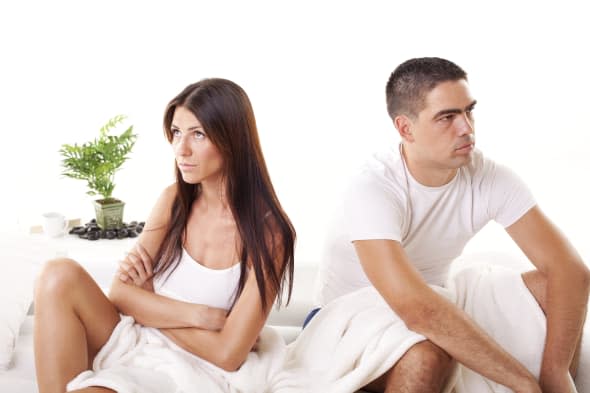 Angry Young couple sitting on the bed because of  Relationship Difficulties.