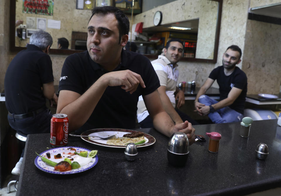 In this Wednesday, June 10, 2020, photo, a man eat his lunch at a restaurant at the Tehran's Grand Bazaar in Iran. As businesses open and people begin to move around more, health experts fear a growing complacency among Iran’s 80 million people may further allow the virus to spread. (AP Photo/Vahid Salemi)