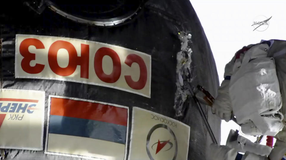 In this image from video made available by NASA, Russian cosmonaut Oleg Kononenko cuts into the insulation on the Soyuz spacecraft attached to the International Space Station on Tuesday, Dec. 11, 2018. Kononenko and Sergei Prokopyev are investigating a mysterious leak which appeared on Aug. 30. (NASA via AP)