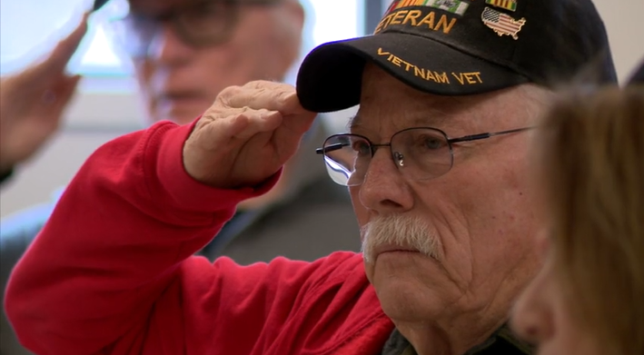 A Vietnam veteran raises his hand to his head in salute