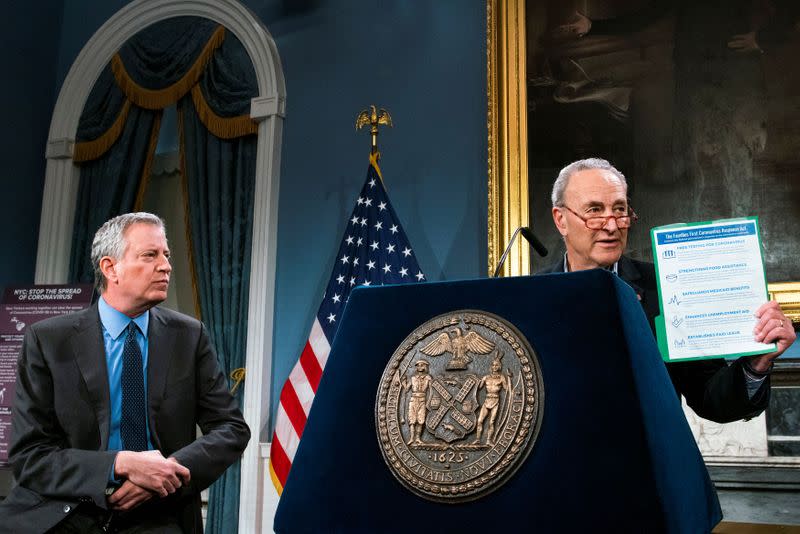 U.S. Senate Minority Leader Schumer, (D-NY) holds a placard with COVID-19 information as he speaks next to New York City Mayor de Blasio during a news briefing of the COVID-19 at the City Hall in the Manhattan borough of New York City, New York