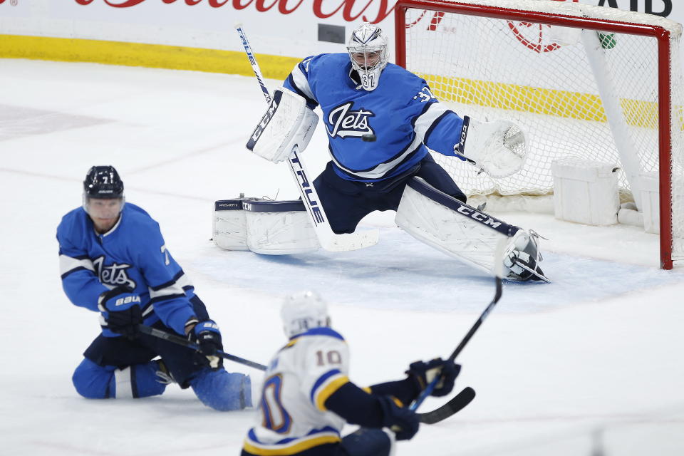 St. Louis Blues' Brayden Schenn (10) scores against Winnipeg Jets goaltender Connor Hellebuyck (37) as Dmitry Kulikov (7) defends during the third period of an NHL hockey game Saturday, Feb. 1, 2020, in Winnipeg, Manitoba. (John Woods/The Canadian Press via AP)