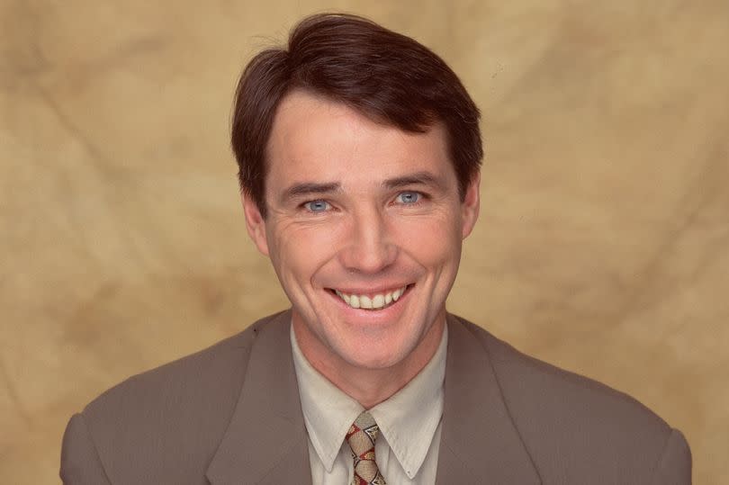 Alan Hansen smiling and pointing towards the red nose day 1995 badge as part of the Red Nose Day 1997 promotional campaign, inside a studio, in London on 14th March 1997.