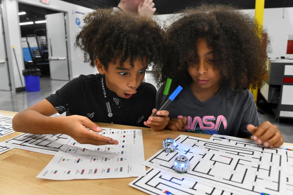 Siblings Jaiden and Julien Wauchope react to tiny robots as they traverse a path they created on paper during an Open Robotics Day at the Hsu Inovation Institute in Fort Walton Beach.