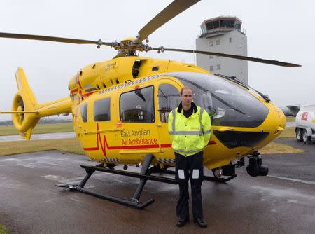 Britain's Prince William poses by his helicopter as he begins his new job as a co-pilot with the East Anglian Air Ambulance (EAAA) at Cambridge Airport, Britain July 13, 2015. REUTERS/Stefan Rousseau/pool