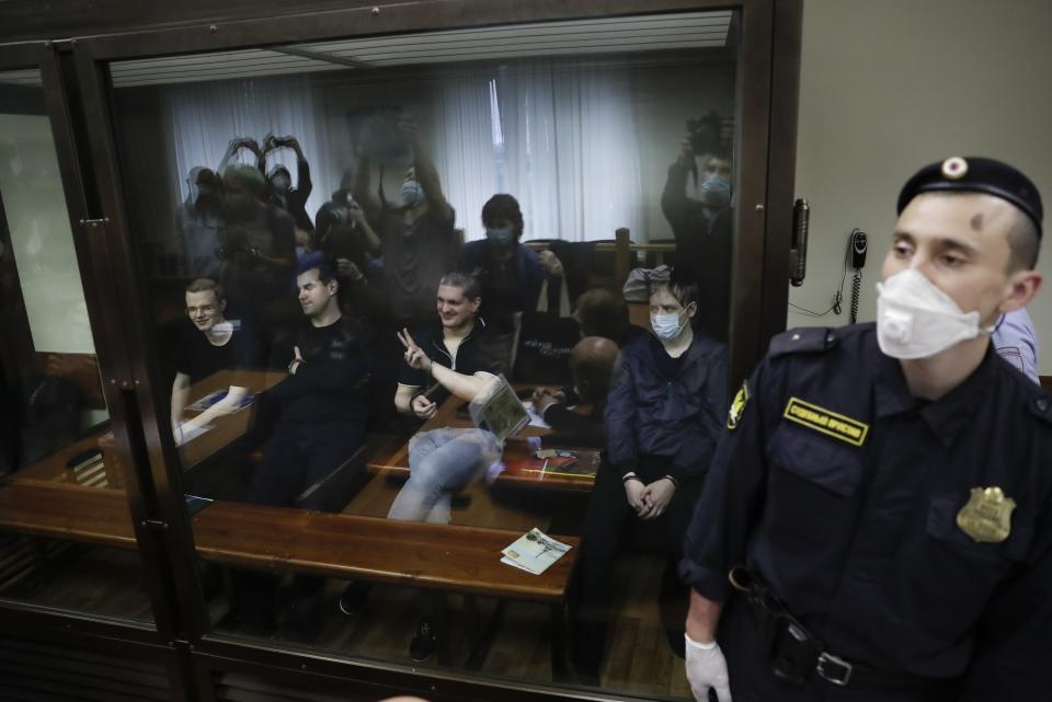 Members of the New Greatness group, who are charged with the organisation of an extremist association, sit behind a glass in a courtroom prior to a court hearing in Moscow, Russia, Tuesday, July 14, 2020. Members of an opposition group dubbed New Greatness were arrested in 2018 on charges of creating an extremist group aiming to overthrow the government. The case was widely criticized as an example of politically motivated abuse anti-extremism laws. (AP Photo/Pavel Golovkin)