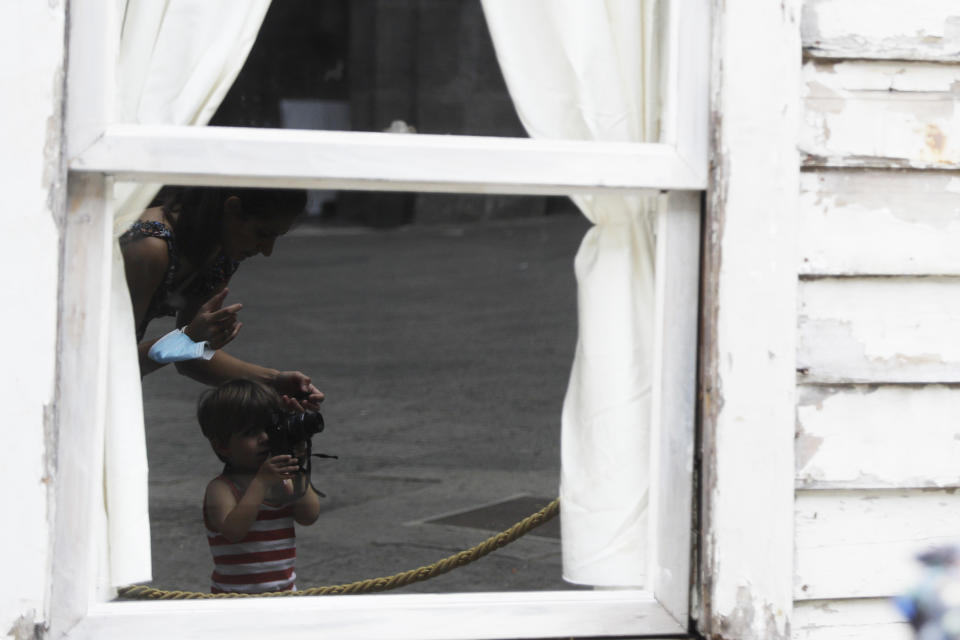 Alice Ridolfi, from Verona, helps her two-year-old son Leone take pictures of the house of U.S. civil rights campaigner Rosa Parks, rebuilt by artist Ryan Mendoza for public display in Naples, Italy, Tuesday, Sept. 15, 2020. The rundown, paint-chipped Detroit house where Parks took refuge after her famous bus boycott is going on display in a setting that couldn't be more incongruous: the imposing central courtyard of the 18th century Royal Palace. (AP Photo/Gregorio Borgia)