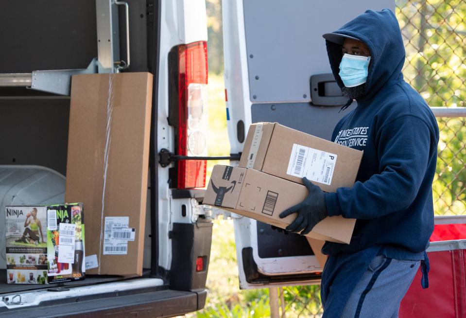 A mailman wearing a mask and gloves to protect himself and others from COVID-19, known as coronavirus, loads a postal truck with packages at a United States Postal Service (USPS) post office location in Washington, DC, April 16, 2020. - For many Americans, checking the mailbox is a daily ritual, a constant in a quickly changing world that can yield anything from wedding invitations to tax audits to new clothes. But as with many ordinary things as the coronavirus crisis unfolds, the US Postal Service -- already compromised by a mountain of debt -- has a most uncertain future. (Photo by SAUL LOEB / AFP) (Photo by SAUL LOEB/AFP via Getty Images)