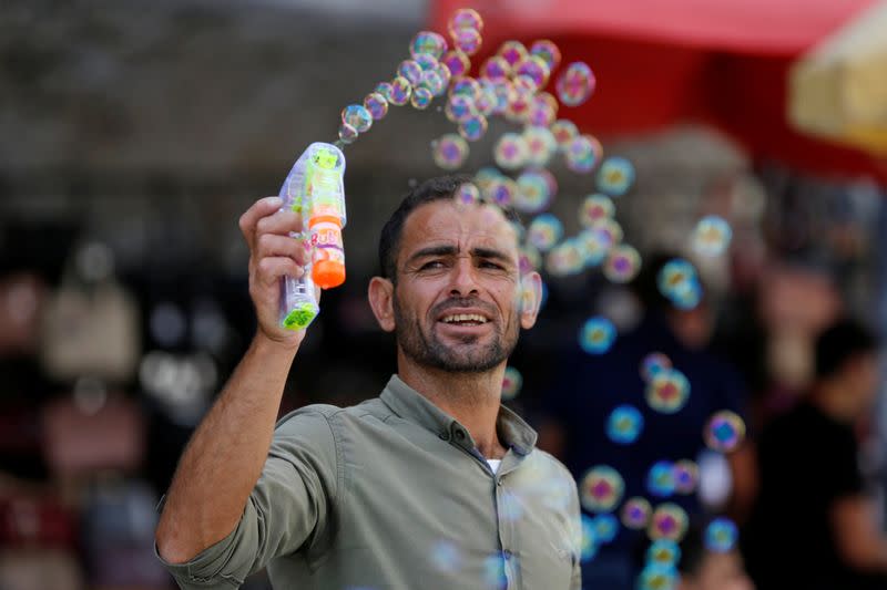 A Palestinian man releases soap bubbles at a market as Palestinians prepare for the upcoming holiday of Eid al-Fitr marking the end of Ramadan,