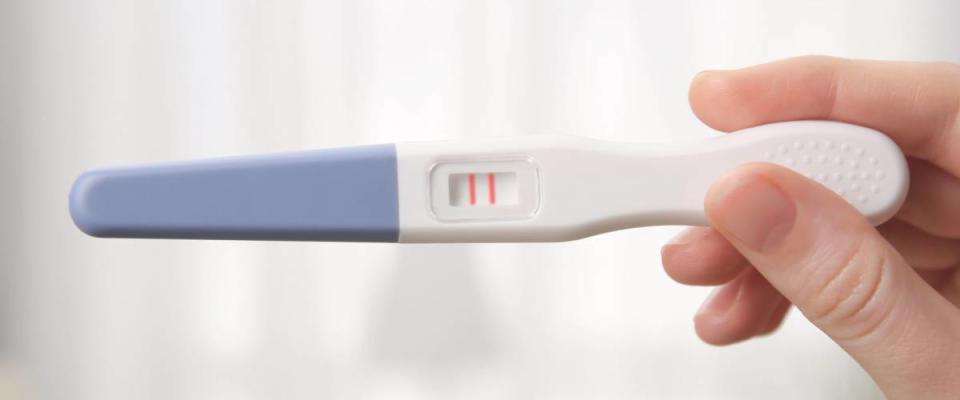 Pregnancy test in female hand on blurred background